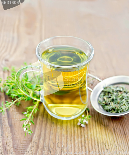 Image of Tea of thyme in mug with strainer on old wooden board