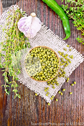 Image of Mung beans in wooden bowl with thyme on dark board top