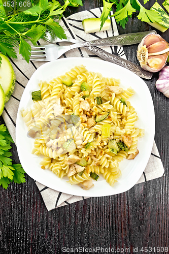 Image of Fusilli with chicken and zucchini in plate on dark board top