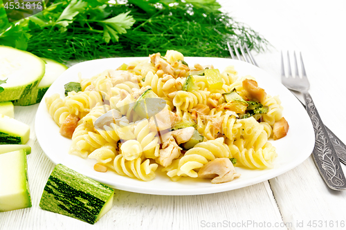 Image of Fusilli with chicken and zucchini in plate on light wooden board