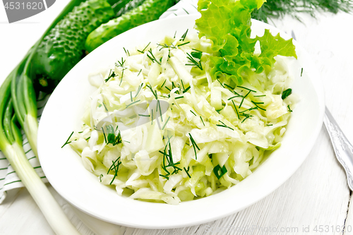 Image of Salad of cabbage and cucumber in plate on light board