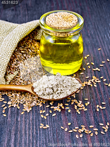 Image of Flour linen in spoon with seeds and oil on dark board