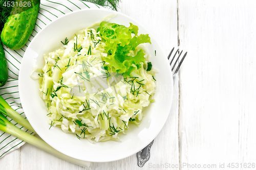 Image of Salad of cabbage with cucumber in plate on board top