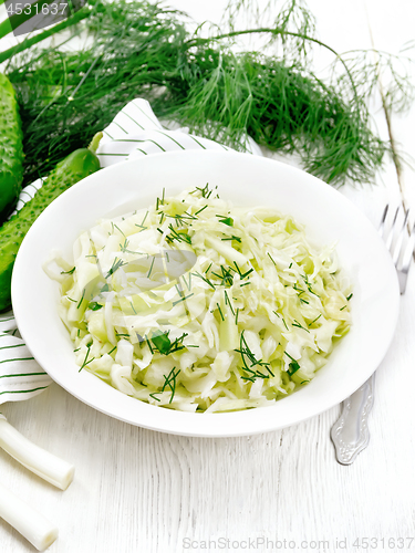 Image of Salad of cabbage and cucumber in plate on board