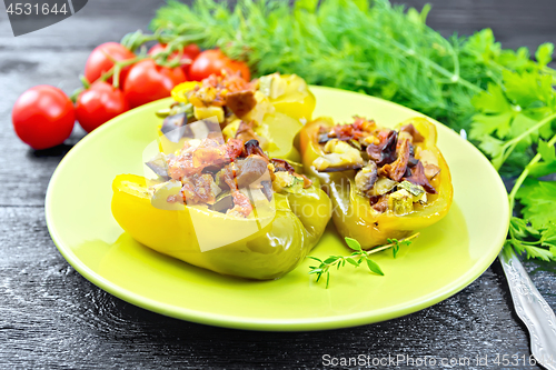 Image of Pepper stuffed with vegetables in green plate on black board