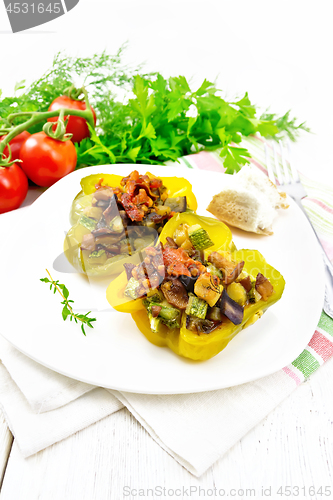 Image of Pepper stuffed with vegetables in plate on light wooden board