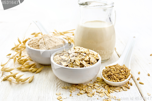 Image of Oat flakes with flour and milk on wooden board