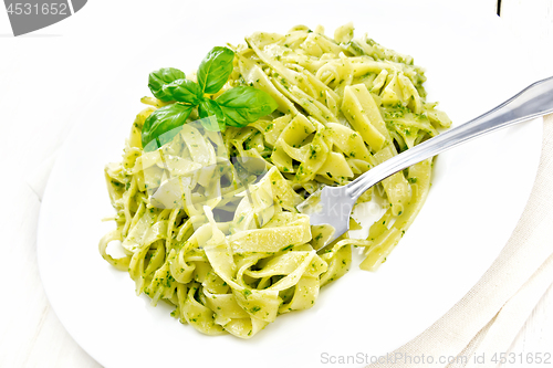 Image of Pasta with pesto sauce in plate on board