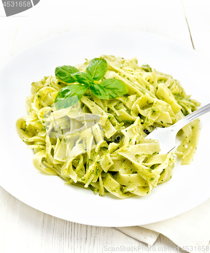 Image of Pasta with pesto sauce in plate on napkin