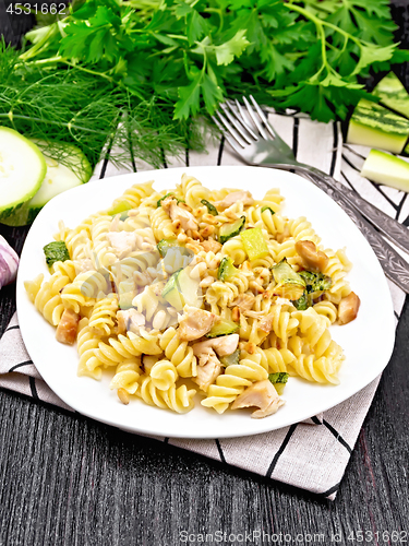 Image of Fusilli with chicken and zucchini in plate on dark board