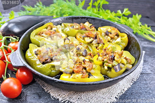 Image of Pepper stuffed with vegetables in pan on wooden board