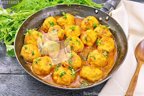 Image of Meatballs in pan with greens on black board