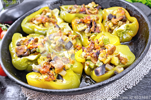 Image of Pepper stuffed with vegetables in pan on black wooden board