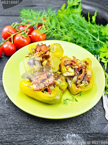 Image of Pepper stuffed with vegetables in green plate on wooden board