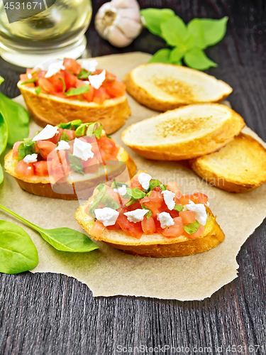 Image of Bruschetta with tomato and cheese on dark wooden board