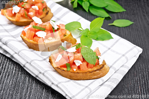 Image of Bruschetta with tomato and feta on dark wooden board