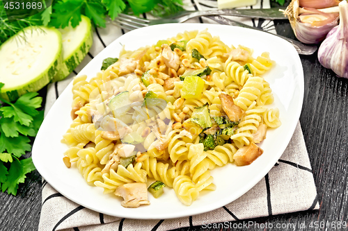 Image of Fusilli with chicken and zucchini in plate on wooden board