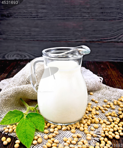 Image of Milk soy in jug with soybeans and leaf on dark board
