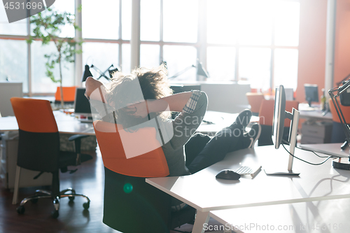 Image of businessman sitting with legs on desk