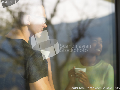 Image of happy multiethnic couple relaxing at modern home indoors