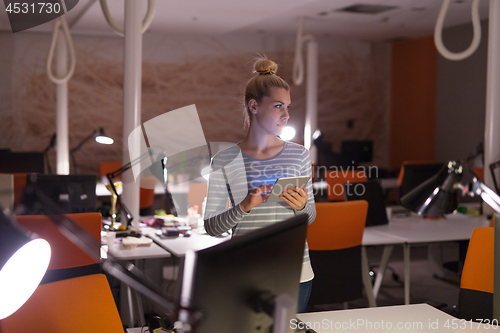 Image of woman working on digital tablet in night office