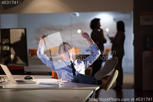 Image of businessman sitting with legs on desk at office