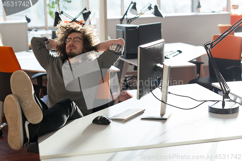 Image of businessman sitting with legs on desk