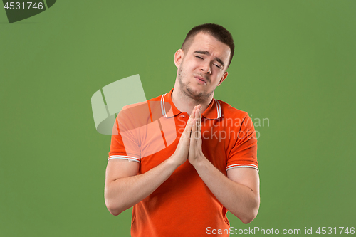 Image of Beautiful male half-length portrait isolated on green studio backgroud. The young emotional surprised man