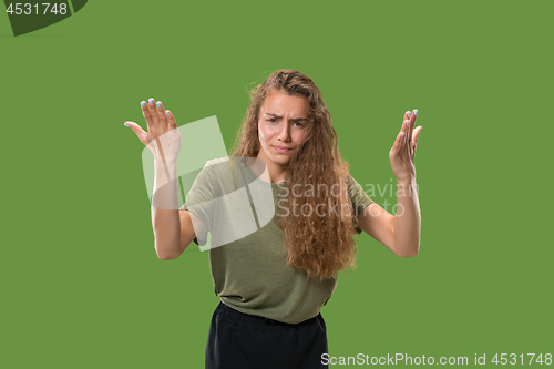 Image of Beautiful female half-length portrait isolated on green studio backgroud. The young emotional surprised woman