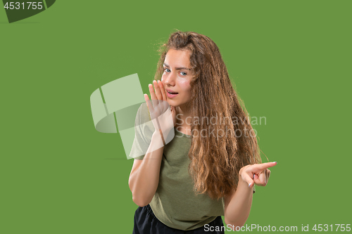 Image of The young woman whispering a secret behind her hand