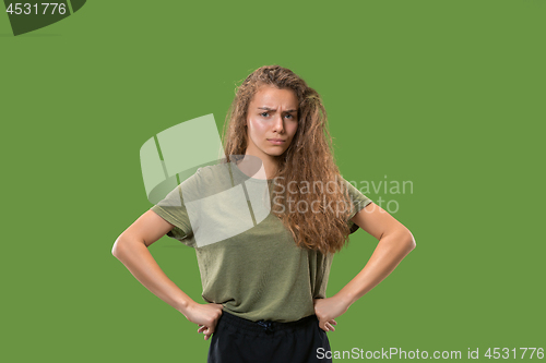 Image of The serious business woman standing and looking at camera against green background.