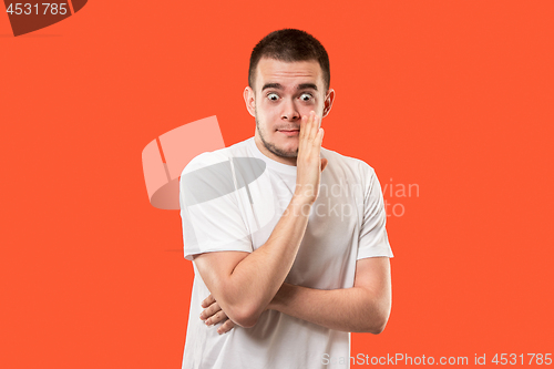 Image of The young man whispering a secret behind her hand over orange background