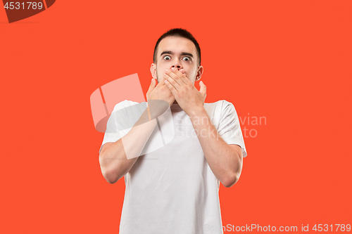 Image of The young man whispering a secret behind her hand over orange background