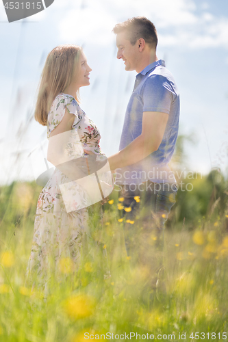 Image of Young happy pregnant couple hugging in nature.