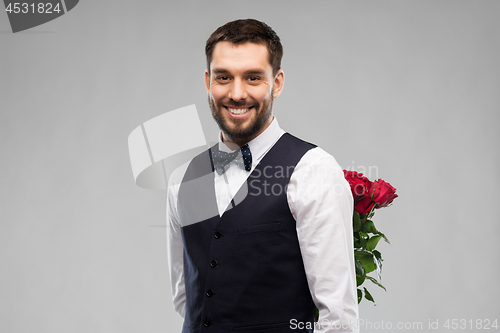 Image of happy man with red roses behind his back