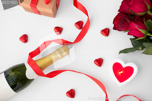 Image of close up of champagne, gift, candies and red roses