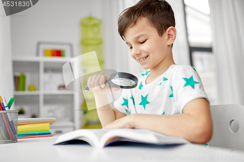 Image of boy with magnifier reading book at home