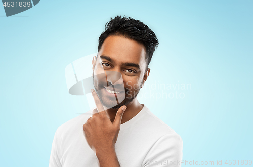 Image of smiling indian man touching his beard