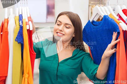 Image of happy woman choosing clothes at clothing store