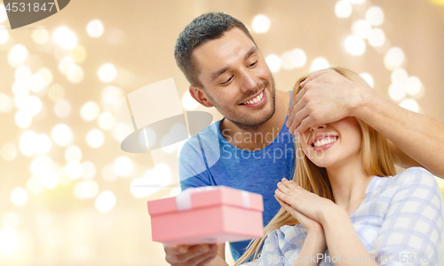 Image of smiling man surprises his girlfriend with present