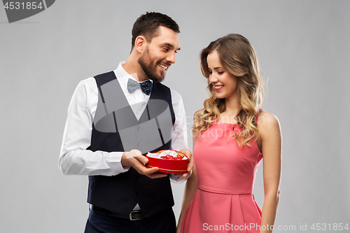 Image of happy couple with chocolate box in shape of heart