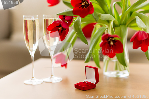 Image of diamond ring, champagne and flowers on table