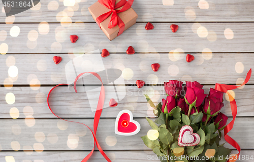 Image of close up of red roses, gift, candies and candle