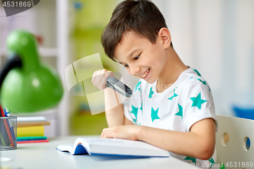 Image of boy with magnifier reading book at home