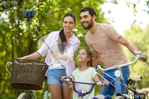 Image of happy family with bicycles taking selfie in summer