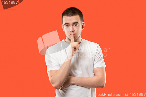 Image of The young man whispering a secret behind her hand over orange background