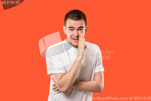 Image of The young man whispering a secret behind her hand over orange background