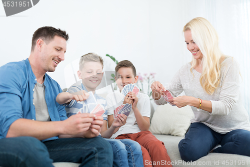 Image of Happy young family playing card game at home.