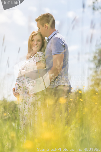 Image of Young happy pregnant couple hugging in nature.