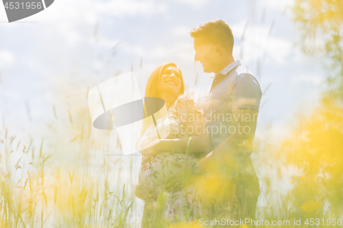 Image of Young happy pregnant couple hugging in nature.